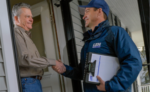 Len The Plumber Heating & Air technician with clipboard shaking homeowner's hand at their front door.