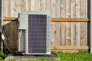 Home air conditioner next to a wooden fence