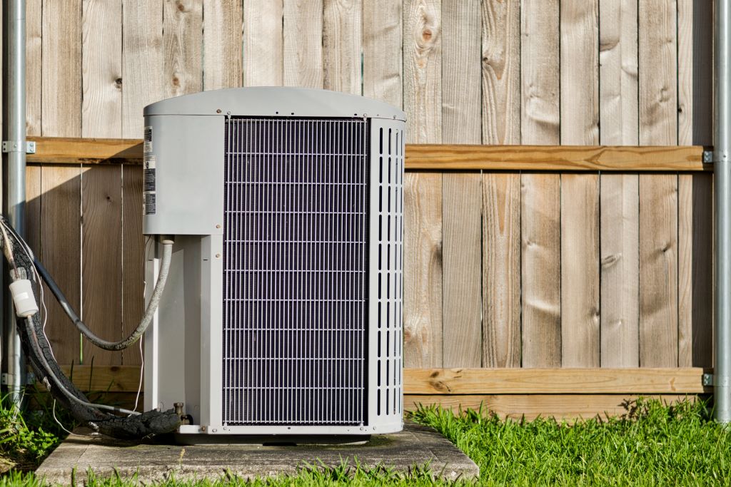 Home air conditioner next to a wooden fence