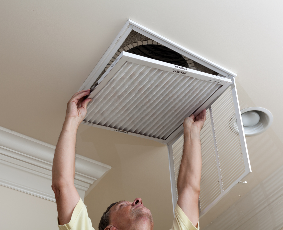 Homeowner changing an air filter in the ceiling
