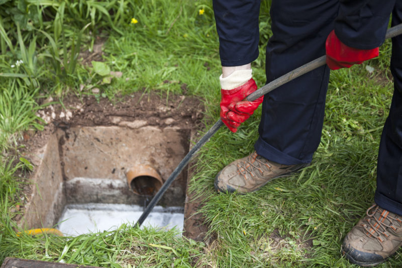 Man cleaning out a sewer in a residential yard