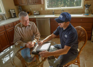 Technician sitting at a kitchen table with a homeowner.