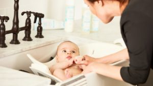 Mother washing baby in sink