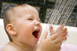 Laughing baby under faucet