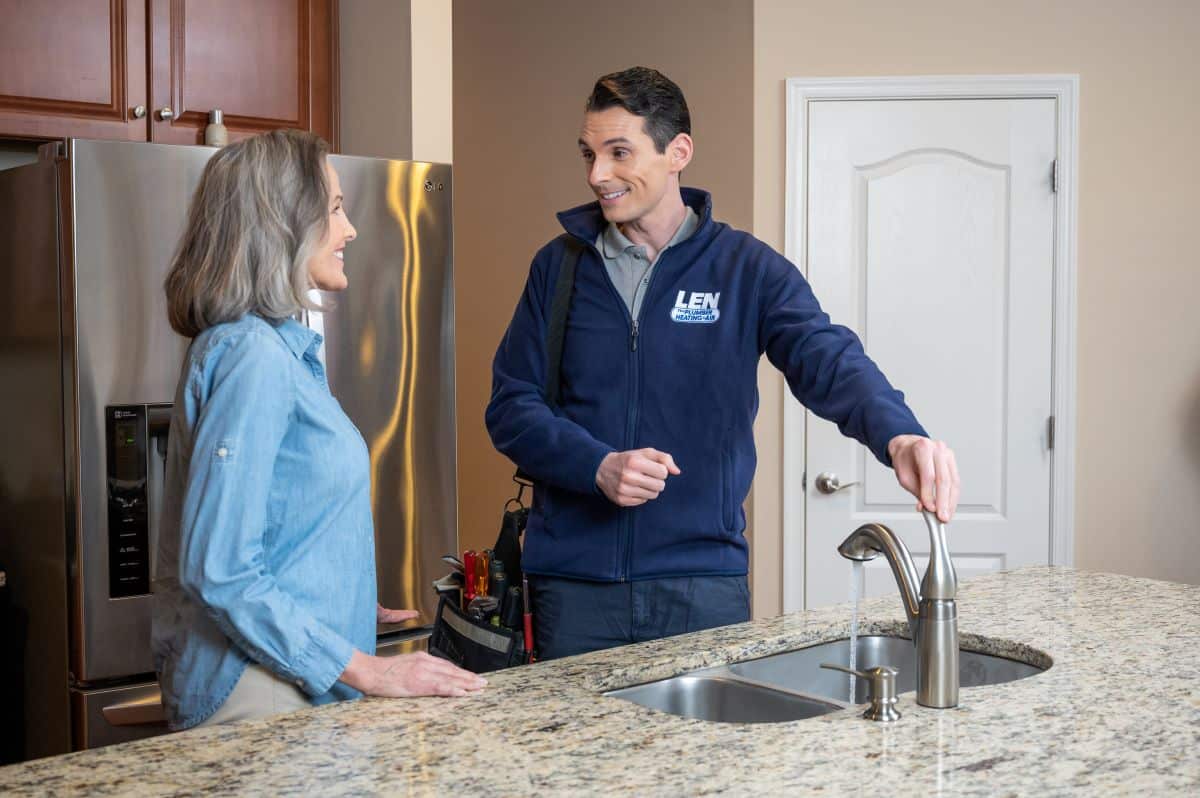 Plumber and homeowner standing by a kitchen sink